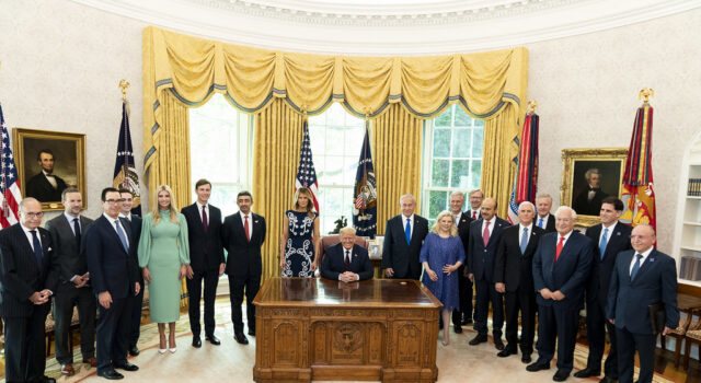 President Trump seated at the Resolute Desk with Israeli, Emirati and Bahraini leaders and U.S. officials standing in the Oval Office